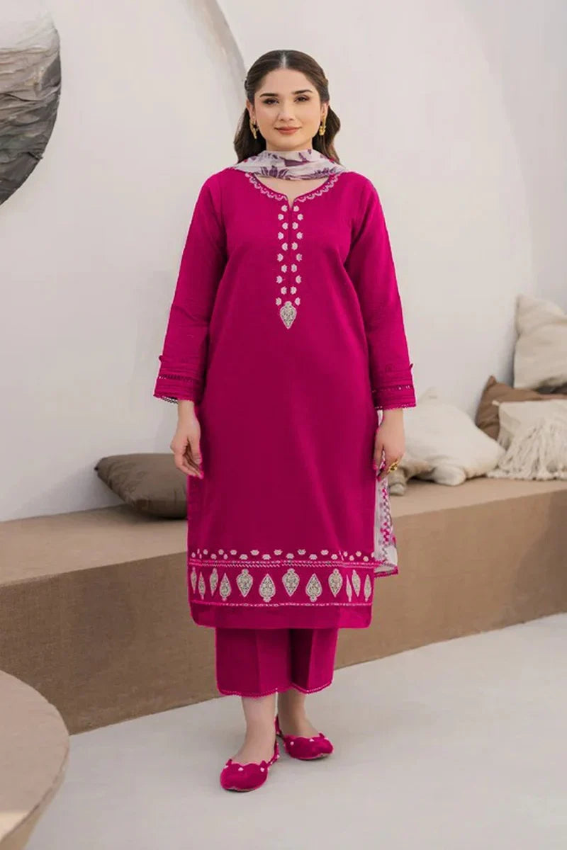 Woman wearing a pink traditional outfit with intricate designs in a minimalistic setting.